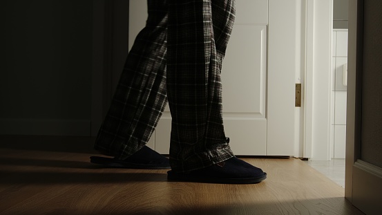 Anciano en pijama y zapatillas camina a un inodoro en casa en la noche photo