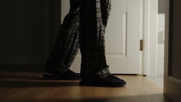 anciano en pijama y zapatillas camina a un inodoro en casa en la noche - puertas baños fotografías e imágenes de stock