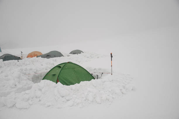 istock Multiple tents standing on snowy ground in fog 1211810705