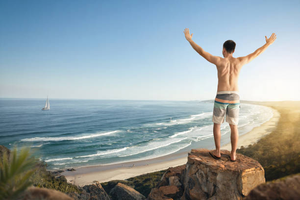 istock Happy man with raised arms above a tropical coast 1211811786