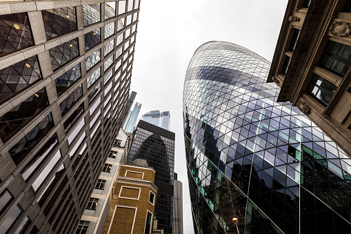 Wide angle image depicting an abstract view looking up at various different modern buildings and futuristic skyscrapers in the city of London, including the gherkin (30 St MAry Axe). Room for copy space.