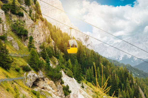 Cable car cabin in the Dolomites mountain blue sky with clouds and forest
