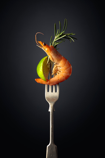 Shrimp with rosemary and lime on a black background. Copy space.