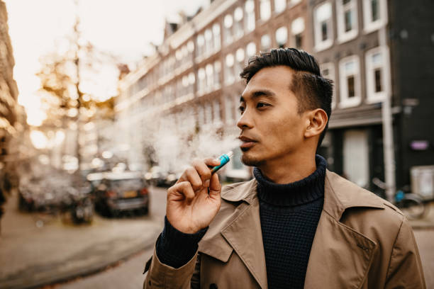 通りで空をしている日本人男性 - 電子タバコ ストックフォトと画像