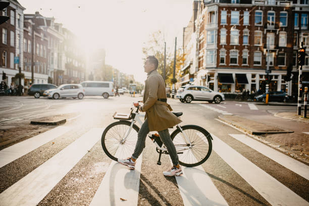 millennial japanischen pendler in der stadt mit dem fahrrad, überqueren die straße - elegante kleidung fotos stock-fotos und bilder