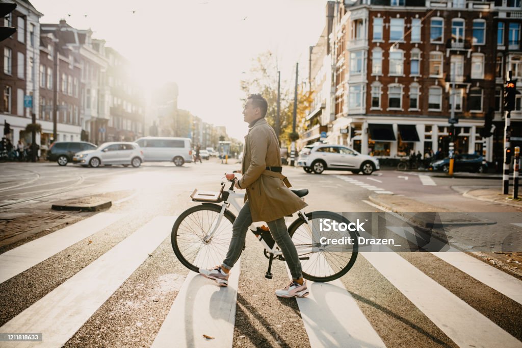 Millennial Japanese commuter in the city with bicycle, crossing the street Commuter with bicycle in the city Cycling Stock Photo