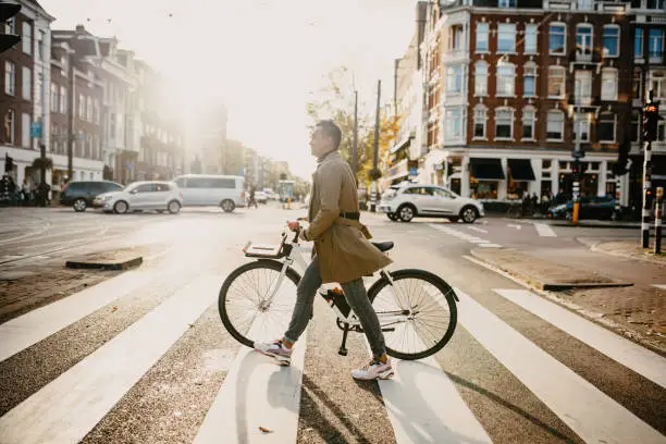 Photo of Millennial Japanese commuter in the city with bicycle, crossing the street