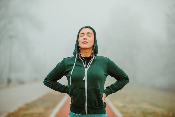 istock Photo of young athlete while she is concentrating before she starts with training session outside on foggy day. 1211823499