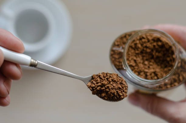 pot en verre avec le café dans une main - coffee granules photos et images de collection