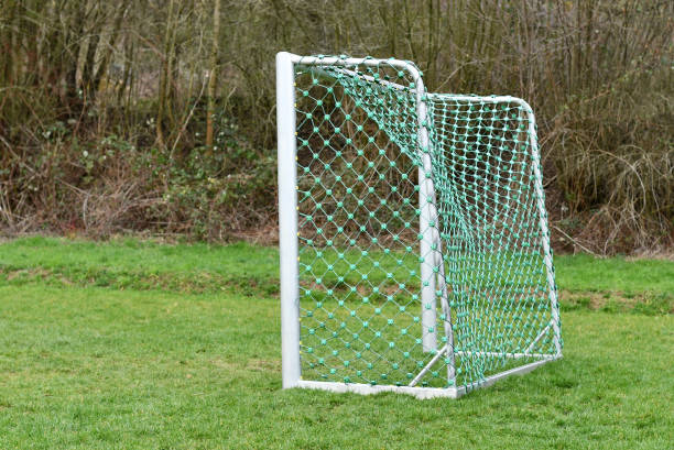 istock Side view of empty soccer goal standing on grass at forest playground 1211826070