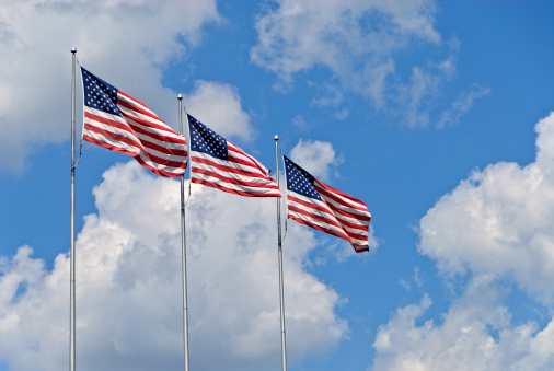 Three American flags in wind against sky