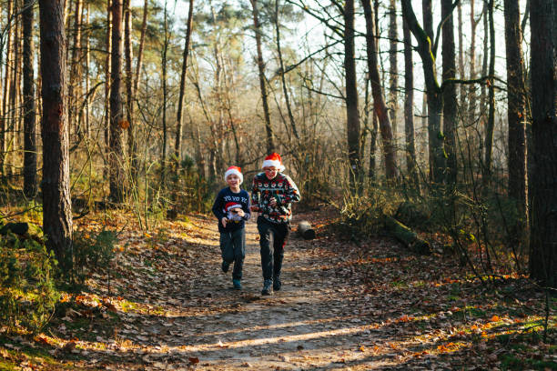Teenager boys in Christmas outfits racing on a path in a forest at sunset stock photo