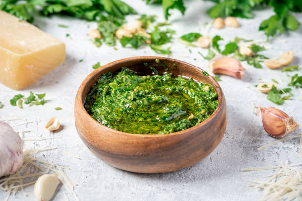 Homemade pesto sauce in a wooden bowl and ingredients for cooking on a gray background Homemade pesto sauce in a wooden bowl and ingredients for cooking on a gray background close-up. Italian food. pesto sauce stock pictures, royalty-free photos & images