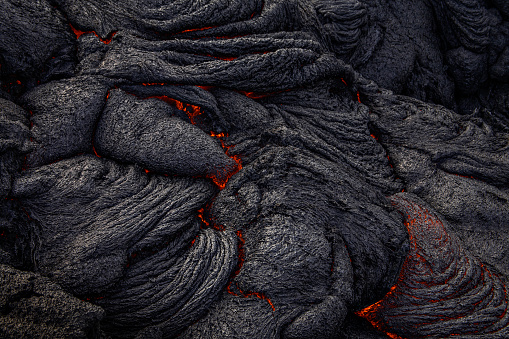 Glowing magma flows between the cracks of lava rock and slowly moves forward on the Big Island, Hawaii
