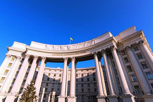 Kyiv, Ukraine-January 29, 2020: Wide-angle landscape view of building with columns of Ministry of Foreign Affairs of Ukraine against blue sky. Ukrainian Trident is coat of arms, Flag of the Ukraine on the top of the building.
