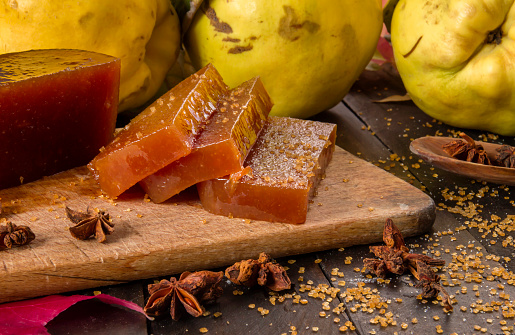 Homemade quince candy slices and raw fruits on rustic wooden table