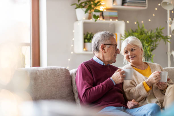 istock Elderly couple drinking coffee together on the sofa at home 1211838255