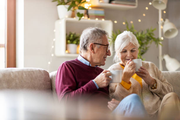 istock Elderly couple drinking coffee together on the sofa at home 1211838263