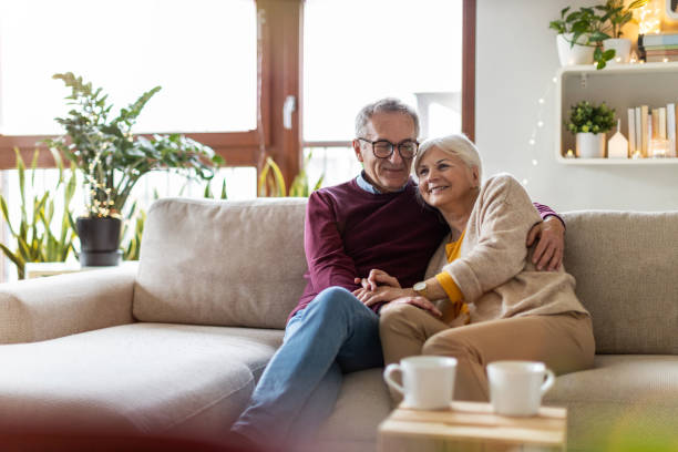 retrato de una pareja de ancianos felices relajándose juntos en el sofá en casa - retirement living fotografías e imágenes de stock