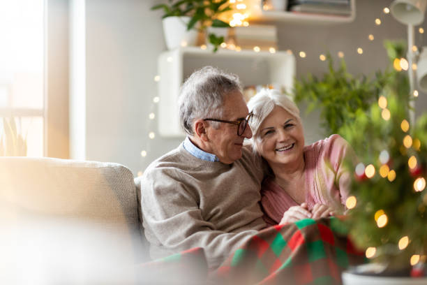 seniorenpaar sitzt zu weihnachten zusammen im wohnzimmer - joy of living stock-fotos und bilder