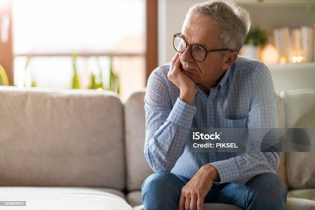 Worried senior man sitting alone in his home Men Stock Photo