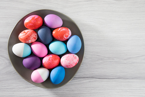 Pastel colored easter eggs in a plate on gray wooden background