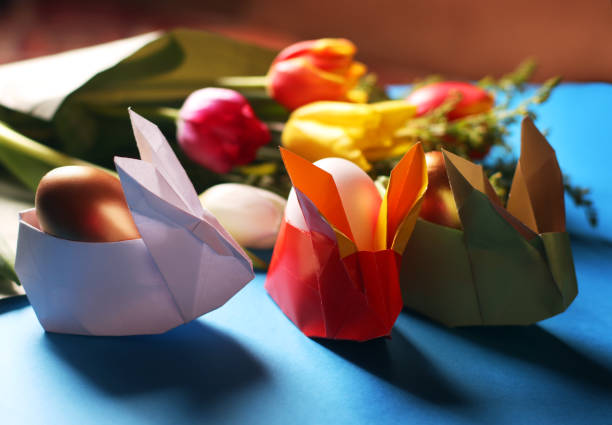 イースター静物。紙のウサギ。イースターゴールデンエッグ。青いテーブルの上に、チューリップの花束。 - easter egg figurine easter holiday ストックフォトと画像