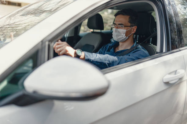 istock man driving a car with a protection mask 1211847671