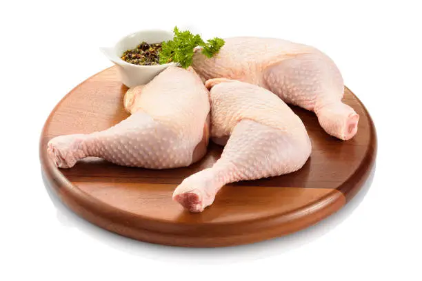 Primal cut of raw chicken legs, with chicken thighs and drumsticks, on a wooden cutting board. Isolated on white background.