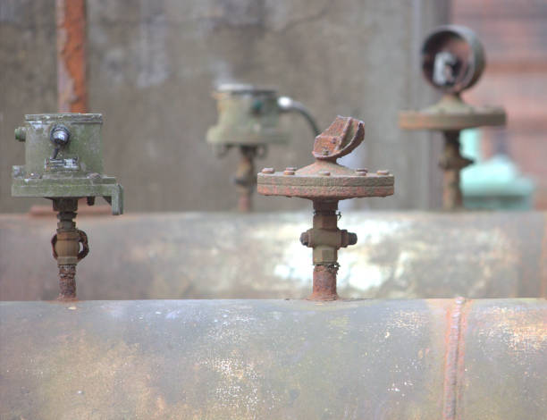various valves on a large rusted pipeline in a disused factory stock photo