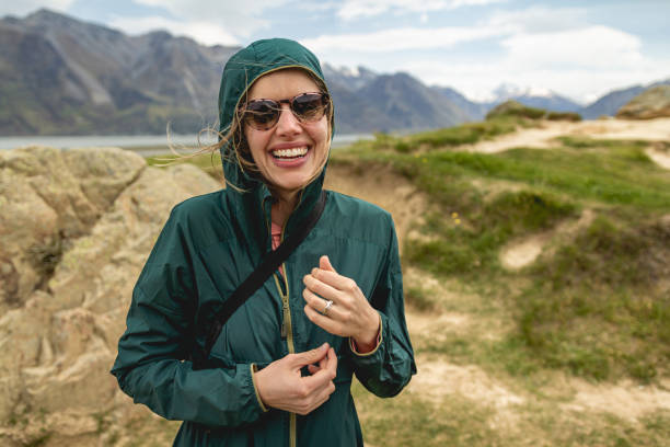 una giovane donna che fa un'escursione in una valle ventosa in nuova zelanda, sede del monte domenica - sunglasses women smiling portrait foto e immagini stock