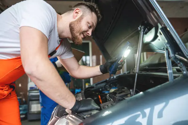 Expert male mechanic teaching his young female trainee