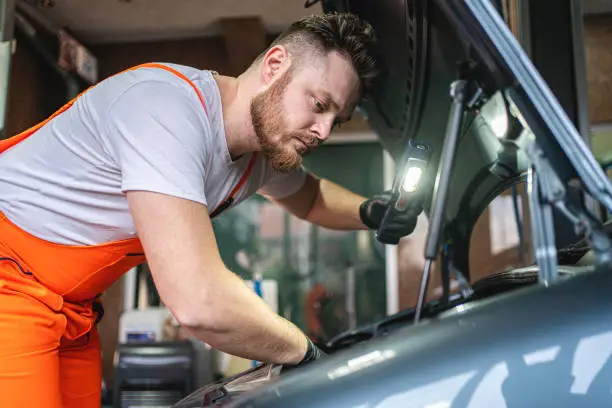 Man inspecting the engine equipment in a broken car