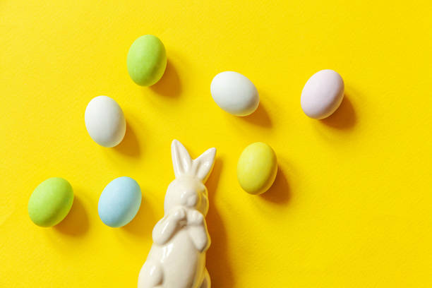 istock Happy Easter concept. Preparation for holiday. Easter candy chocolate eggs sweets and bunny toy isolated on trendy yellow background. Simple minimalism flat lay top view copy space 1211858107