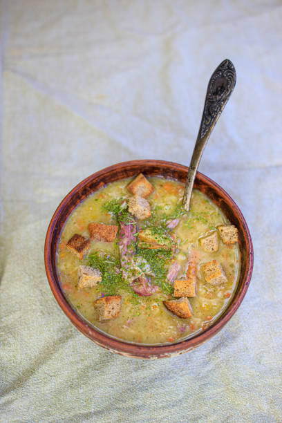 istock Pea soup with smoked meat, crackers and herbs in a rustic clay plate on a light linen tablecloth. Minimalism Life style, naturalness. Copy space 1211860137