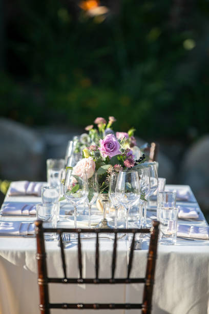 istock Table setting for a wedding ceremony with white tablecloth and crystal, decorated with flowers in vases 1211860904