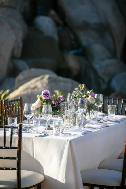 istock Table setting for a wedding ceremony with white tablecloth and crystal, decorated with flowers in vases 1211861426