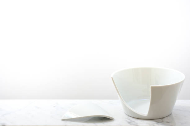 istock A broken white ceramic bowl stands against a white background on a light marble plate with space for text 1211861935