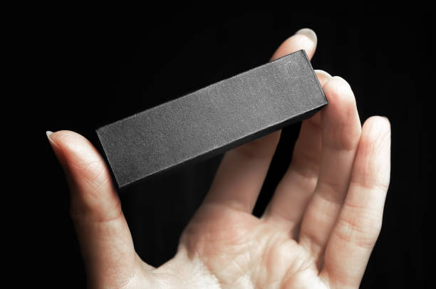 Female hand holding blank black box or cosmetic package