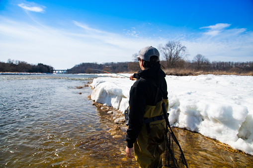 A fisherman fishing for rainbow trout on a late winter day.
