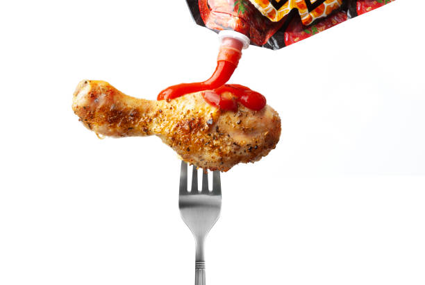 istock Chicken leg with ketchup on a fork isolated on white 1211866158
