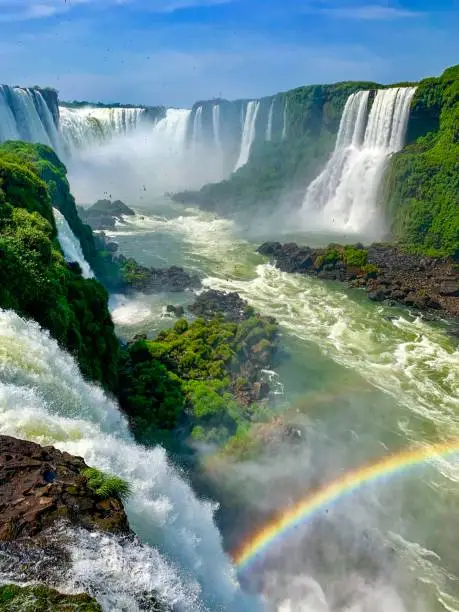 A rainbow forms against the backdrop of the beautiful Iguazu Falls, located between Brazil and Argentina in South America.