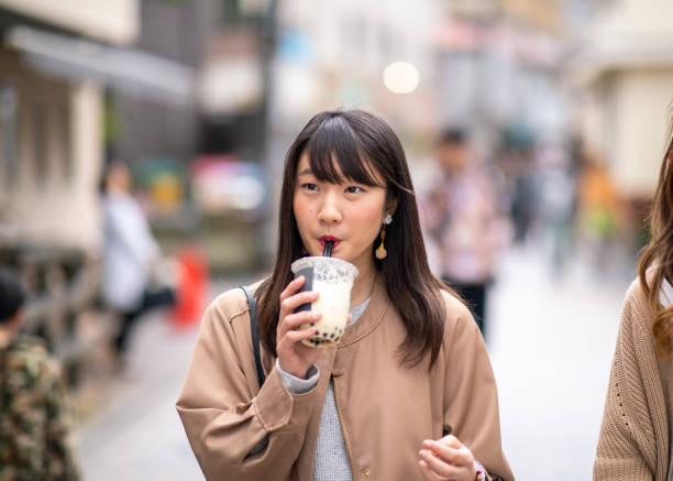 Young woman drinking tapioca tea on street stock photo