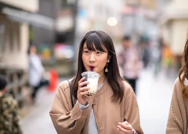 Young woman drinking tapioca tea on street