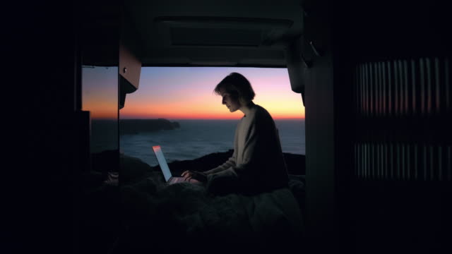 Una joven empresaria está trabajando en su computadora en una furgoneta camper. photo
