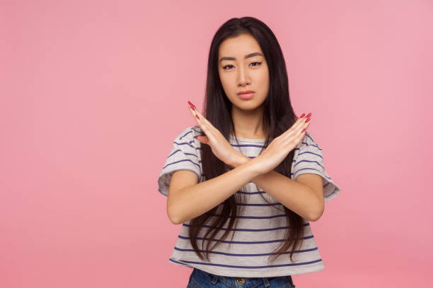 まさか、やめなさい!ストライプのtシャツでブルネットの髪を持つ深刻な女の子の肖像画は、クロスハンドでxサインを作ります - conflict one way sign road sign ストックフォトと画像