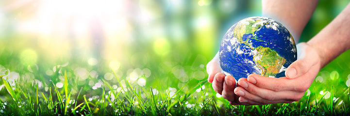 Hands Holding Planet Earth In Lush Green Environment With Sunlight - Earth Day Concept - Some Elements Of This Image Were Provided By NASA\nhttps://earthobservatory.nasa.gov/images/565/earth-the-blue-marble\nCreated With Adobe Photoshop