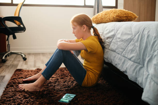 Preteen Bullied Girl Feeling Lonely And Sad At Home Little girl feeling depressed after reading text message on mobile telephone in home bedroom. Concept of bullying and loneliness among preteens pre adolescent child stock pictures, royalty-free photos & images