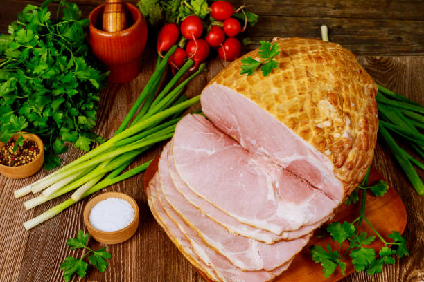 istock Dinning table with whole baked and sliced ham, vegetables and spice. 1211901127