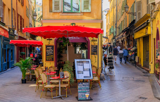 Tourists visit the pedestrian zone, commercial landmark with restaurants and shops in traditional houses in Nice, France Nice, France - June 2, 2019: Tourists visit the pedestrian zone, commercial and cultural landmark with restaurants and shops in traditional houses facade store old built structure stock pictures, royalty-free photos & images